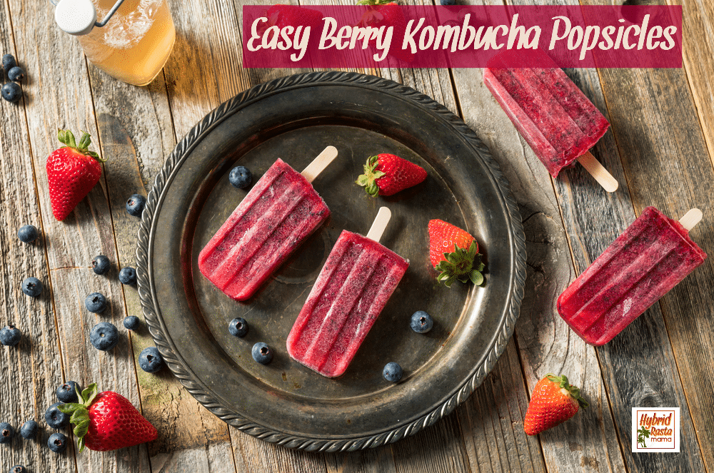 Homemade berry kombucha popsicles on a fancy brown platter surrounded by berries