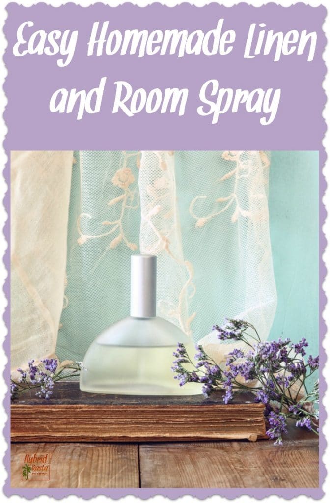 A clear perfume bottle with linen and room spray surrounded by sprigs of lavendar and a cream lace curtain in the backgroun.