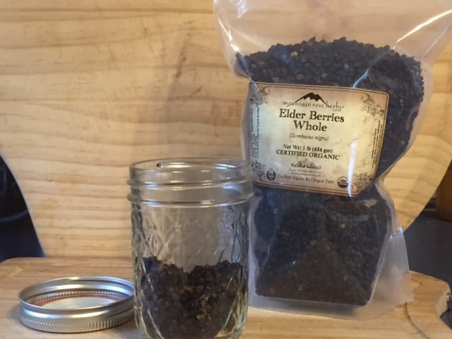 Mason jar filled halfway with dried elderberries for an elderberry elixir