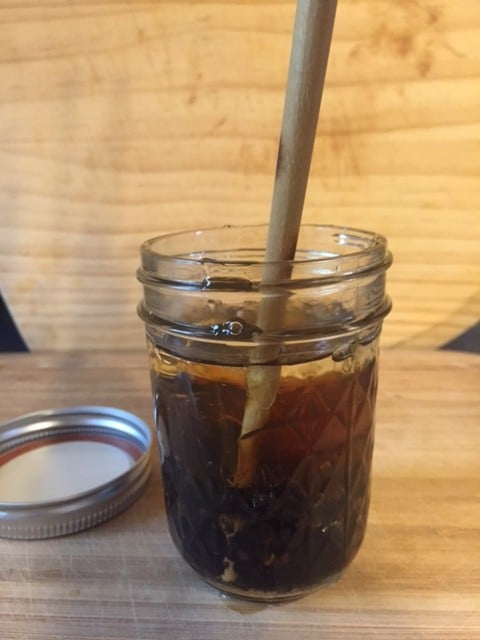 Stirring elderberry elixir in mason jar with a chopstick