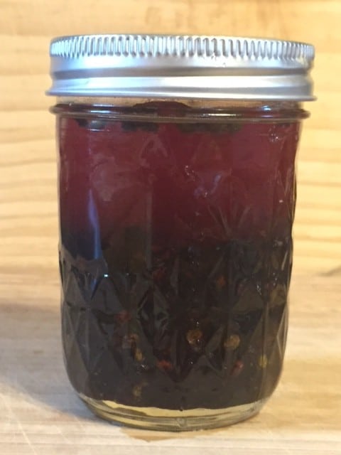 Elderberry elixir in mason jar against light wood background