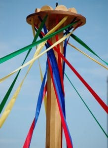 Maypole with colored ribbons unfurling, sunny skies