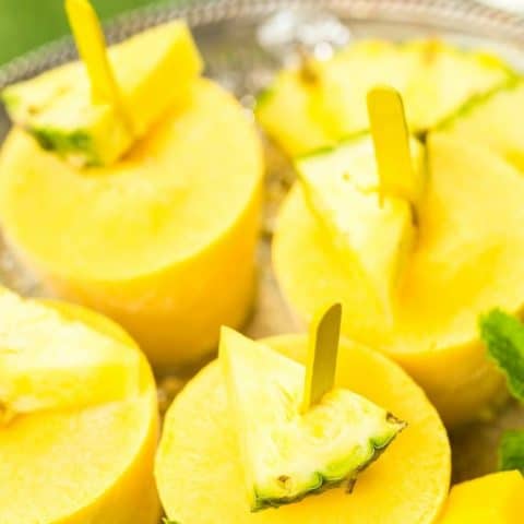 pineapple coconut milk popsicles with fresh pineapple slices on them